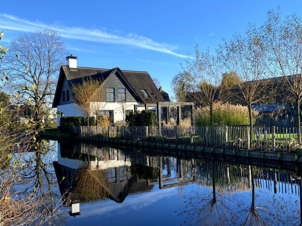Landelijke tuin in de winter weerspiegelt in de naastgelegen sloot met schapenhek als afrastering.