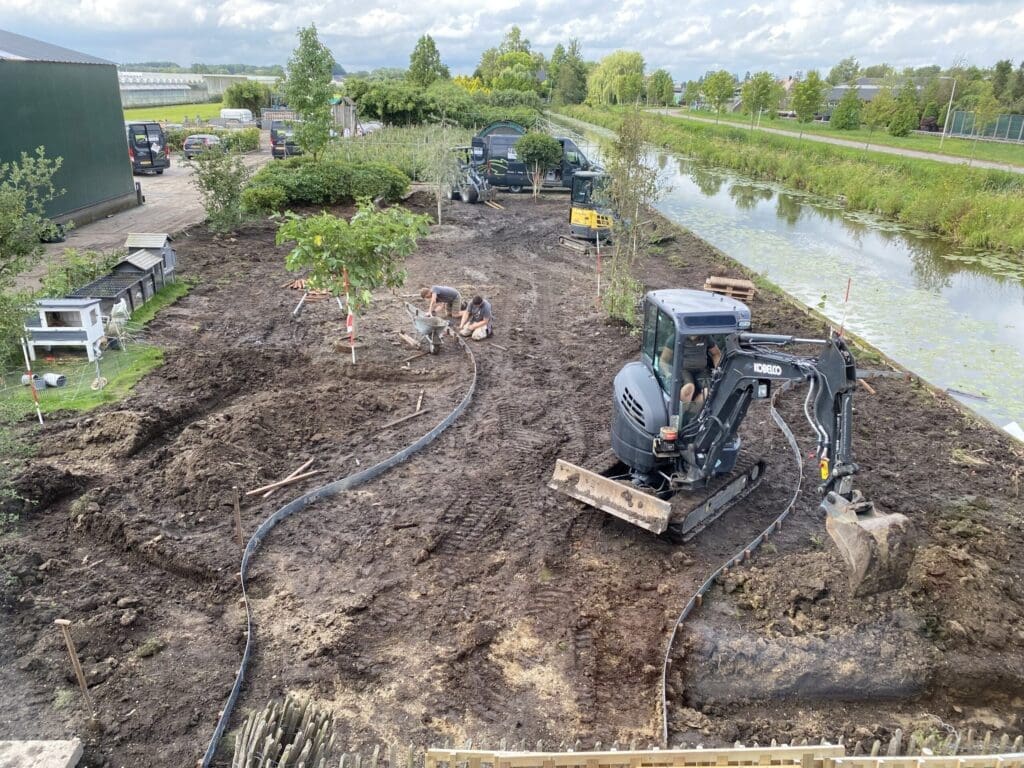 Overzichtsfoto van landelijke tuin in aanleg met uitzetten van lijnen in organische vormen met strips.