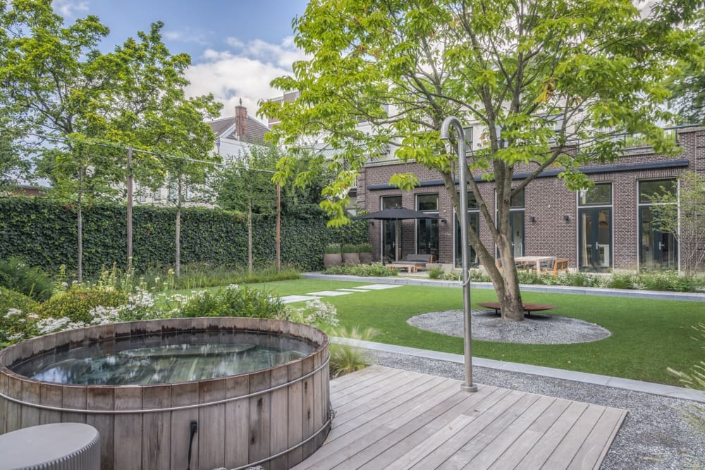 kleine vlonder met hottub en buitendouche naast een mooie groene border