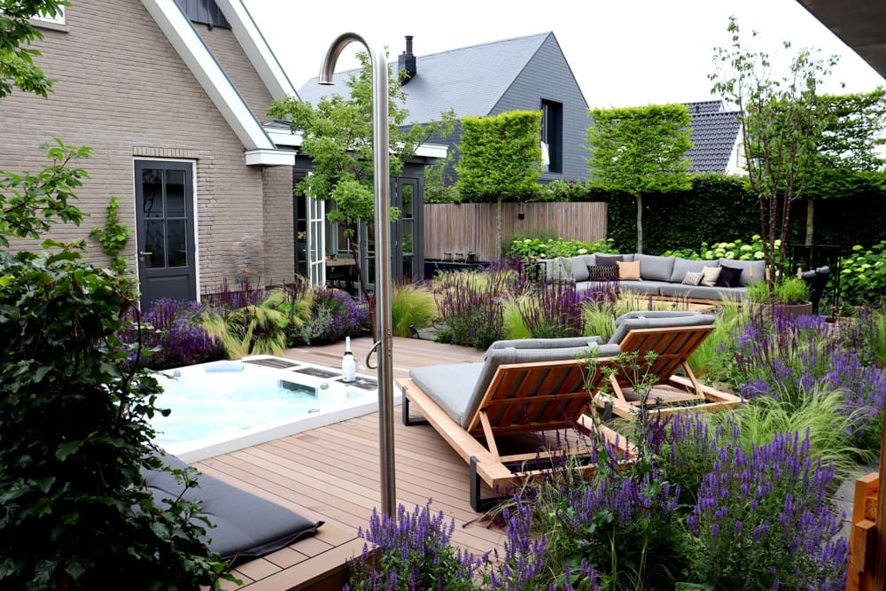 vlonder met ingebouwde jacuzzi en buitendouche tussen de kleurrijke bloemen