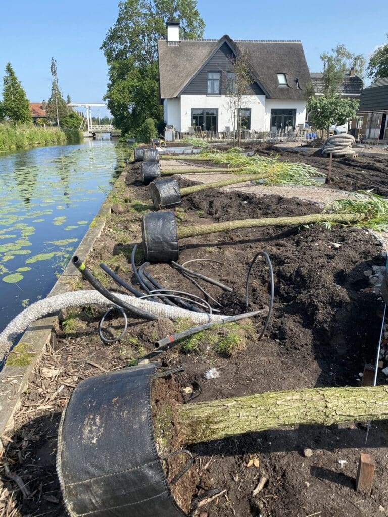 Wilgen liggen klaar om gepoot te worden langs de slootkant en drainage wordt voorbereid.