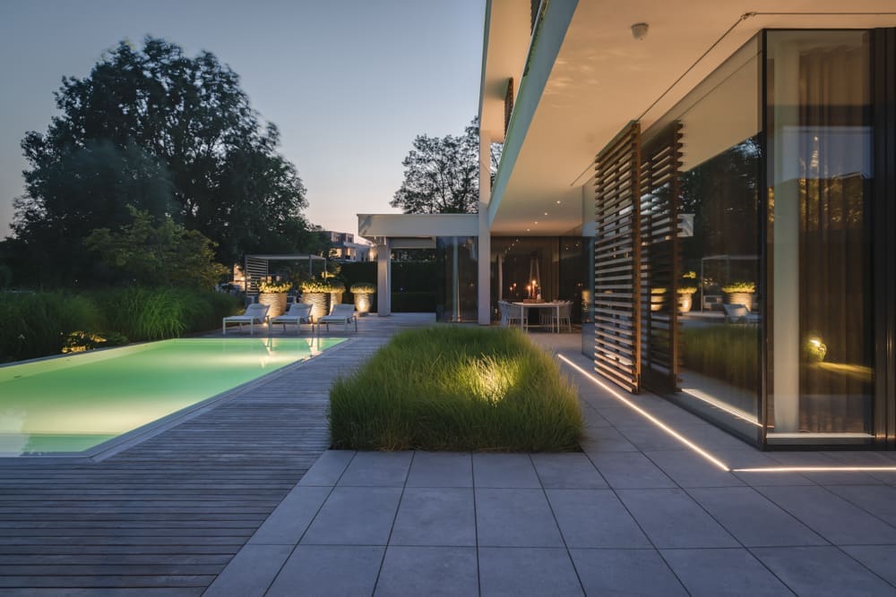 terras met ledstrip in de tegels en een volle border met grassen
