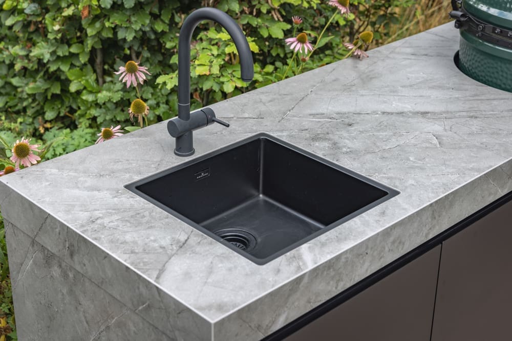 mooie strakke wasbak met zwarte kraan in de buitenkeuken