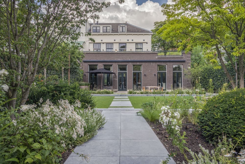 lang pad richting het huis tussen de groene borders door en tussen het gazon