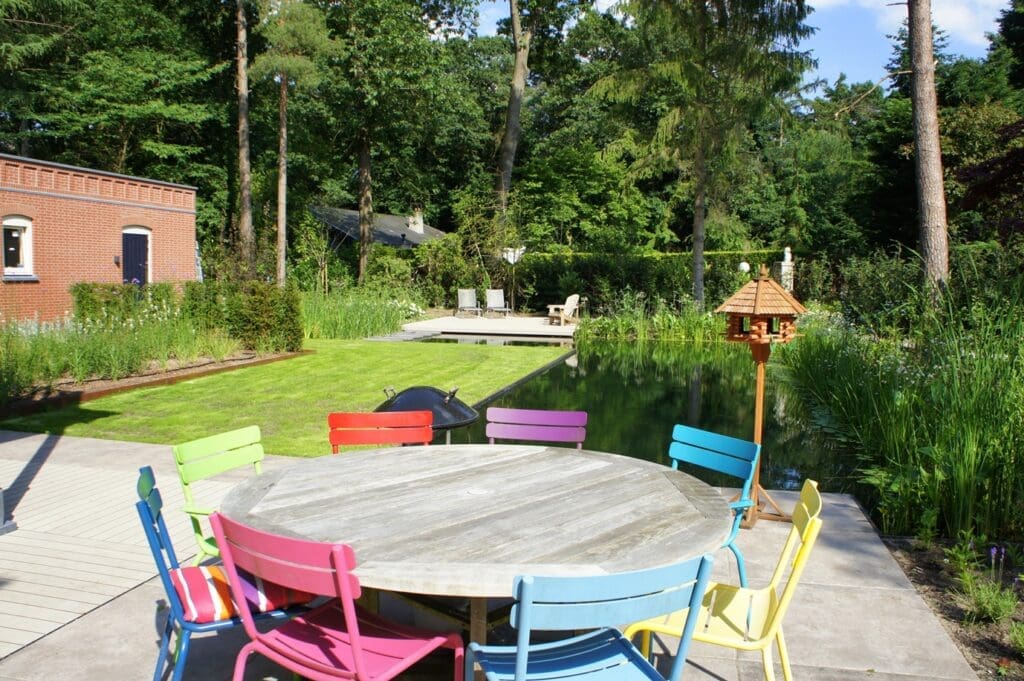 terras met eettafel met op de achtergrond de zwemvijver en het gazon