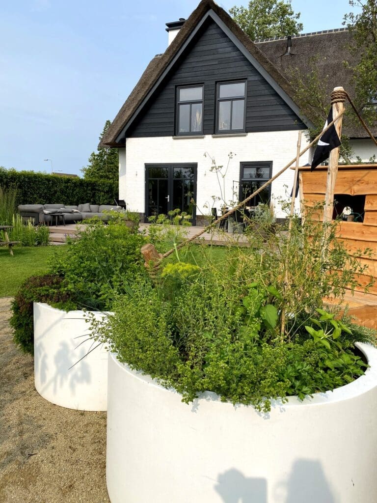 Witte ronde Adezz kruidenbakken in landelijke tuin met witte rietgedekte villa