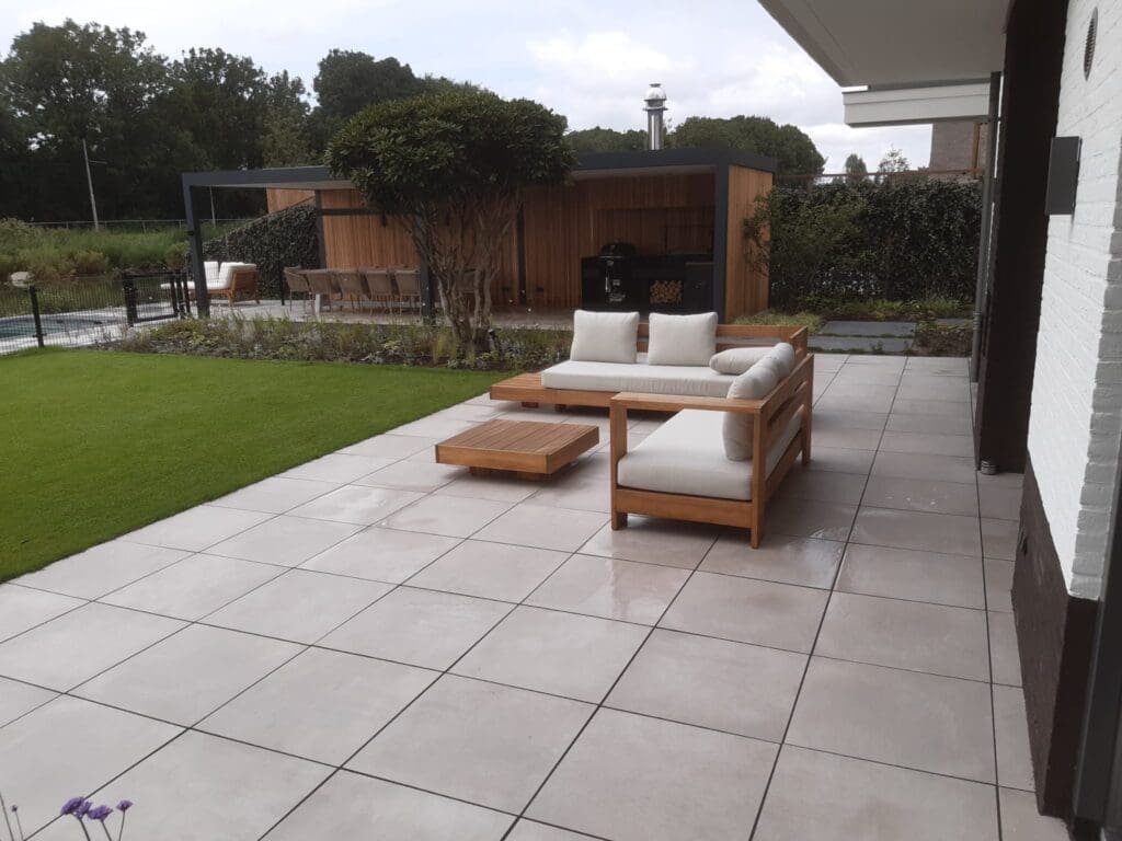 terras met witte tegels en houten loungeset