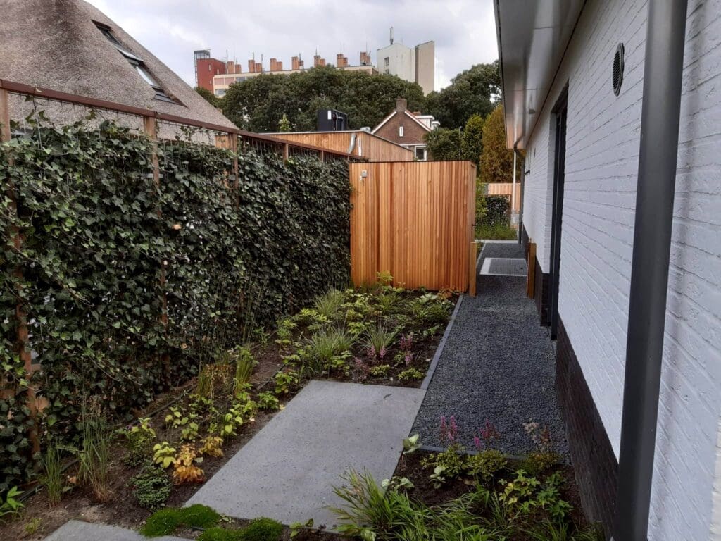 zijtuin met staptegels en grindpad naar houten schuurtje