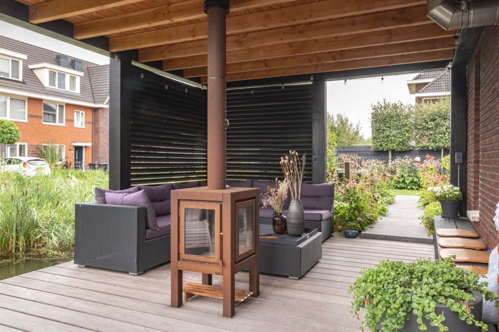 overkapping op de vlonder aan het water met een loungeset naast de kachel