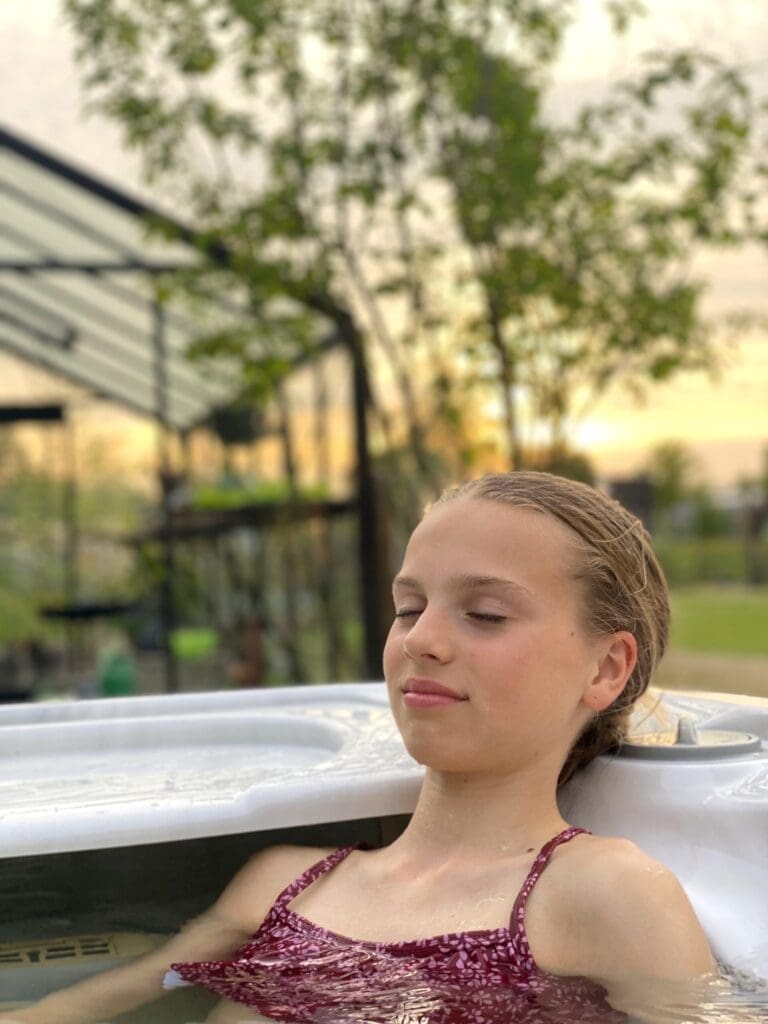 Tiener geniet met ogen dicht in jacuzzi buiten.