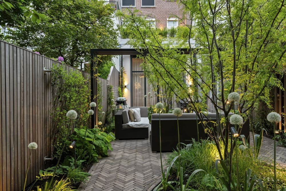 12 klinkerterras mooie groene borders om het klinkerterras heen met sfeervolle loungeset onder de pergola