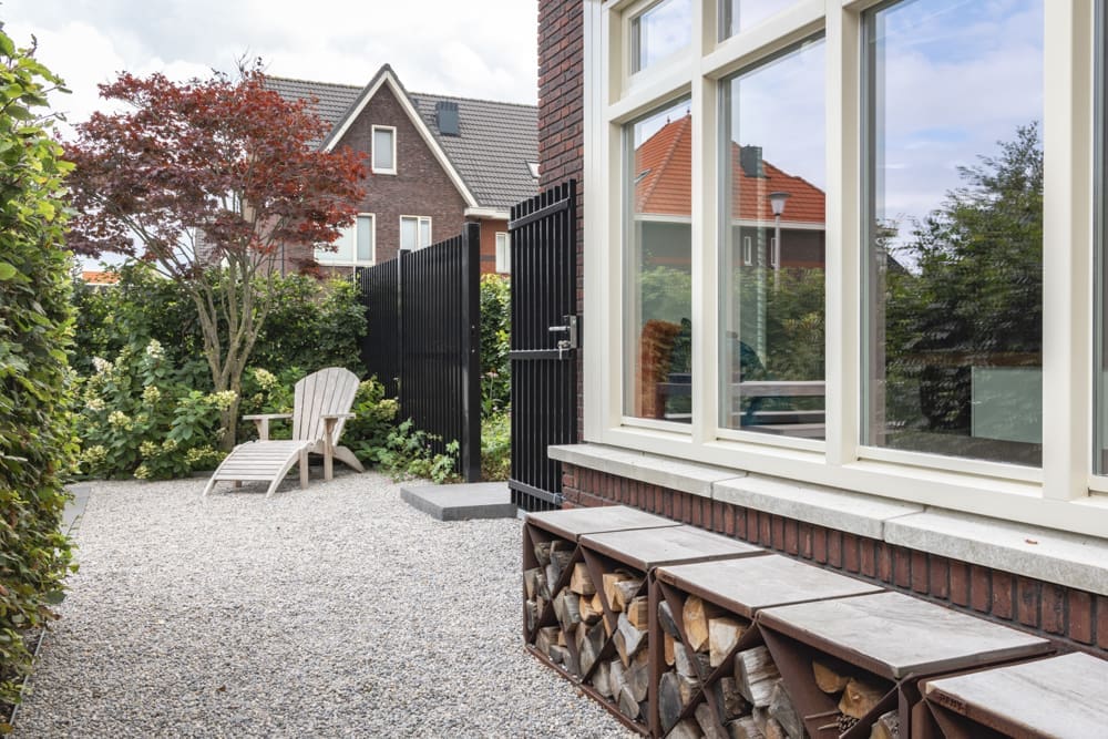 groot grindpad langs het huis met ligbed naast het hek