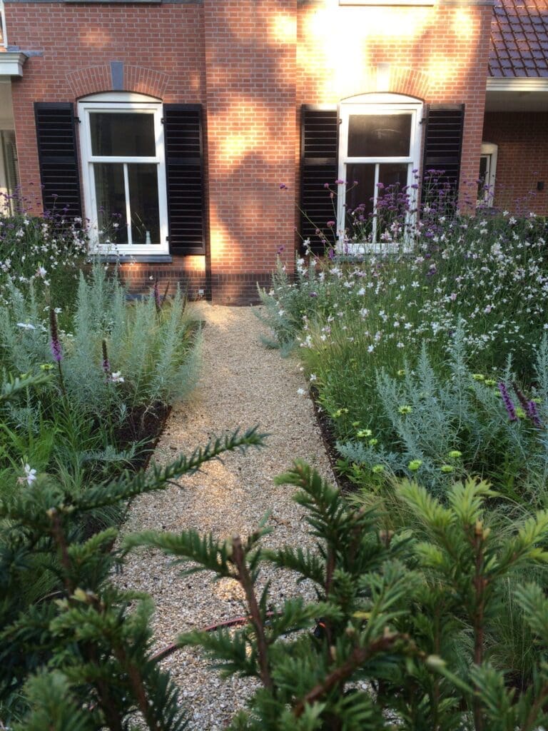 grindpad in de zijtuin tussen de kleurrijke borders