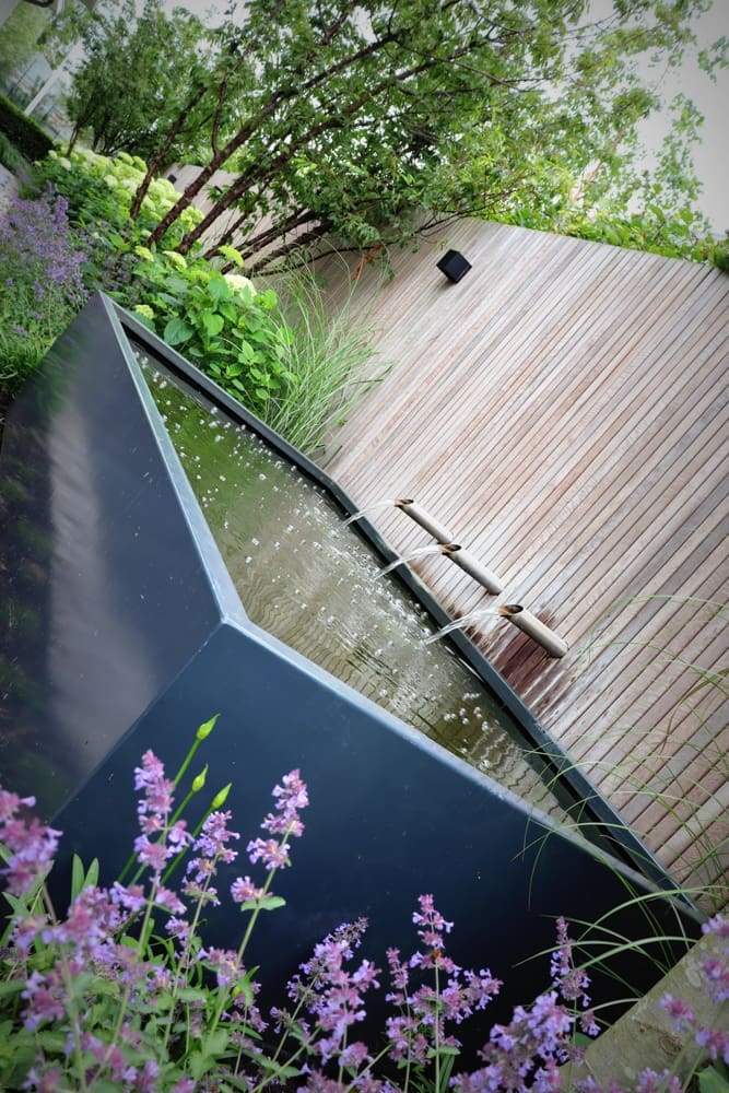 polyesterbak met waterloop tegen de houten schutting aan
