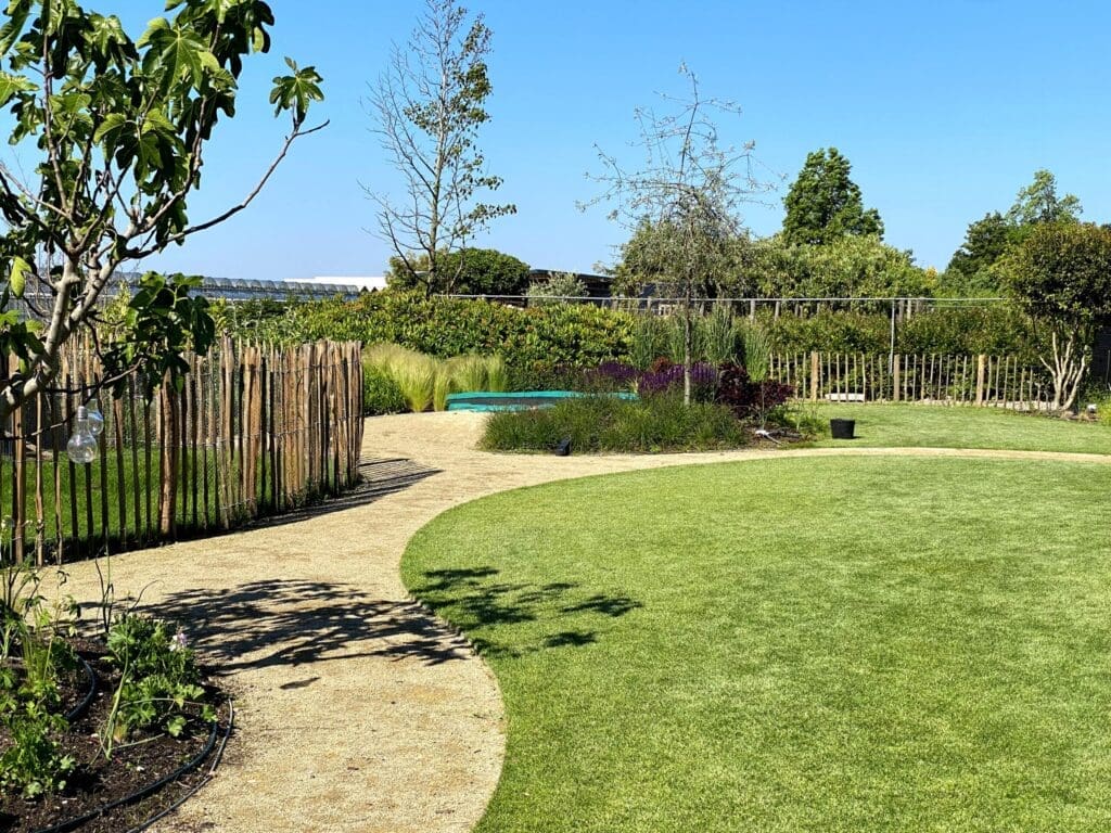 Zonnige landelijke tuin met net aangeplante borders en groen gazon.