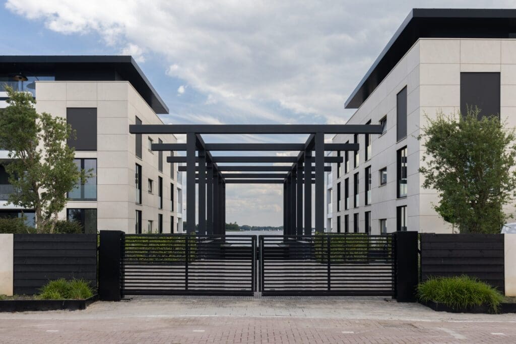 inrit met stalen hek stalenhek met reuzen pergola daar achter