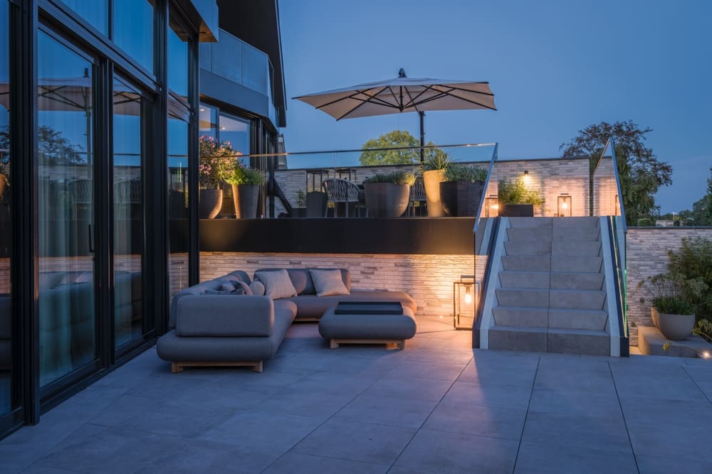beneden terras met loungebank en boven terras met eettafel en sfeerlampen