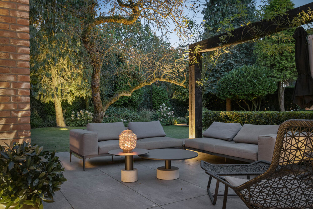 sfeervolle zithoek in het avondlicht met op de achtergrond het gazon en de mooie bloemen zee.