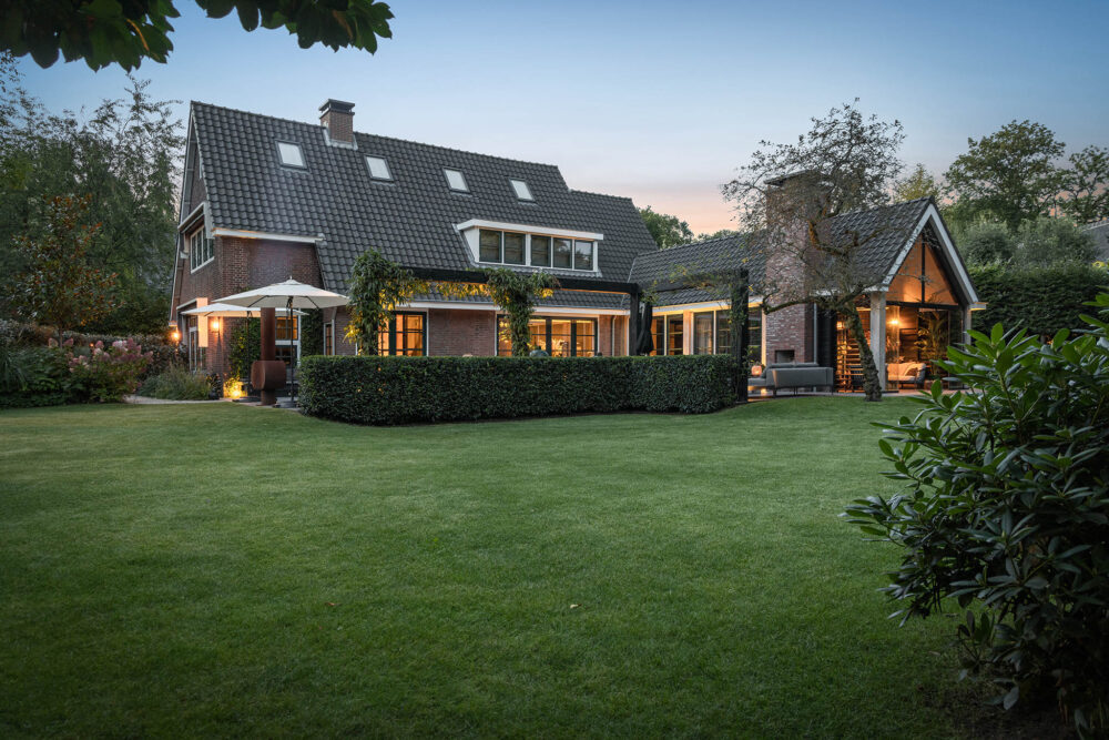 mooi strak gazon met op de achtergrond het sfeervolle terras in het avond licht