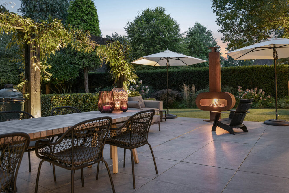 landelijke tuin met terras in avondlicht met begroeide pergola