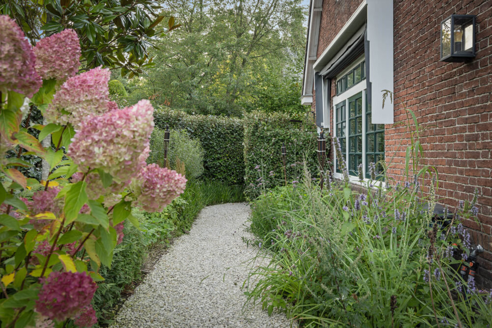 zijtuin met grindpad met een kleurrijke bloemenzee er om heen