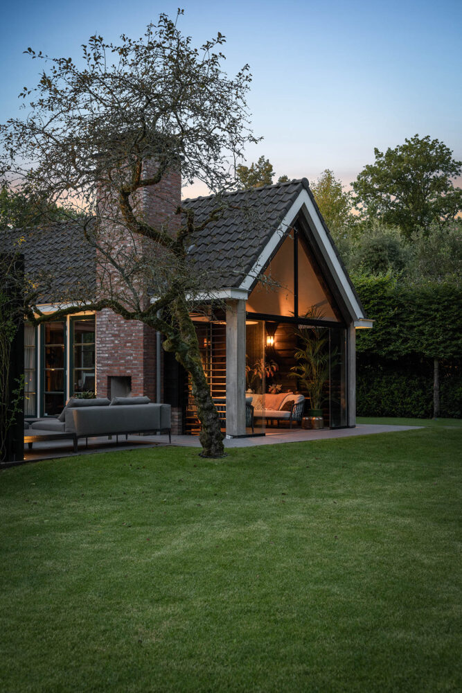 mooi stuk gazon met lounge en sfeervolle overkapping op de achtergrond