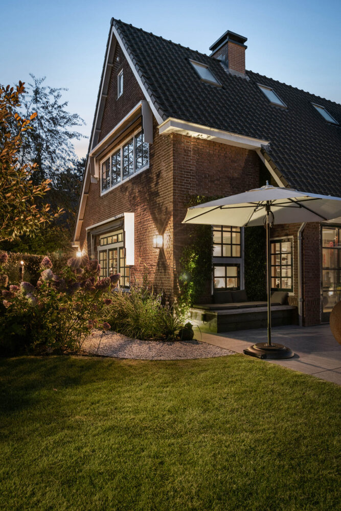 de zijtuin in het avondlicht met grindpad tussen de kleurrijke borders