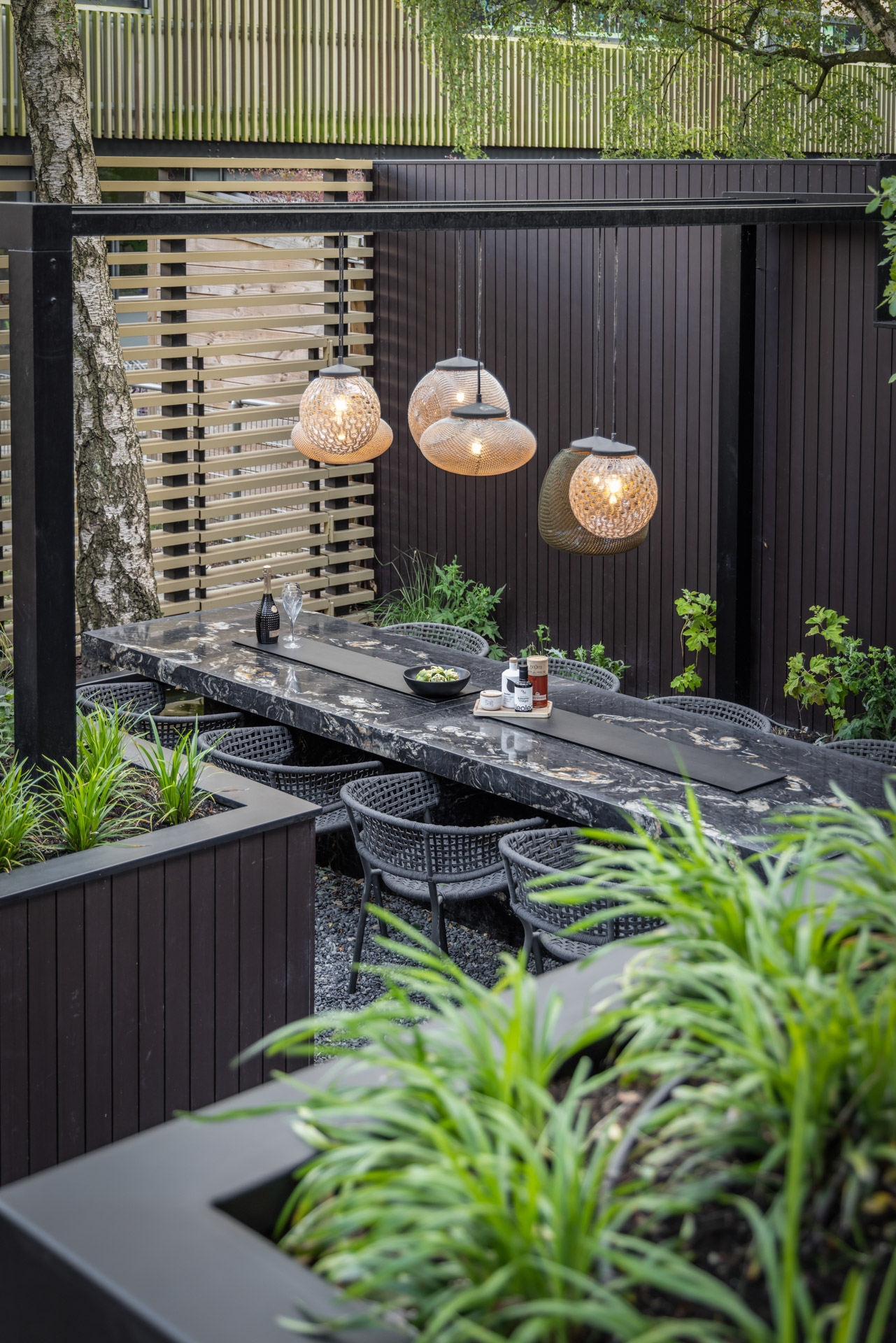 eethoek met hanglampen aan de pergola op het grindvlak