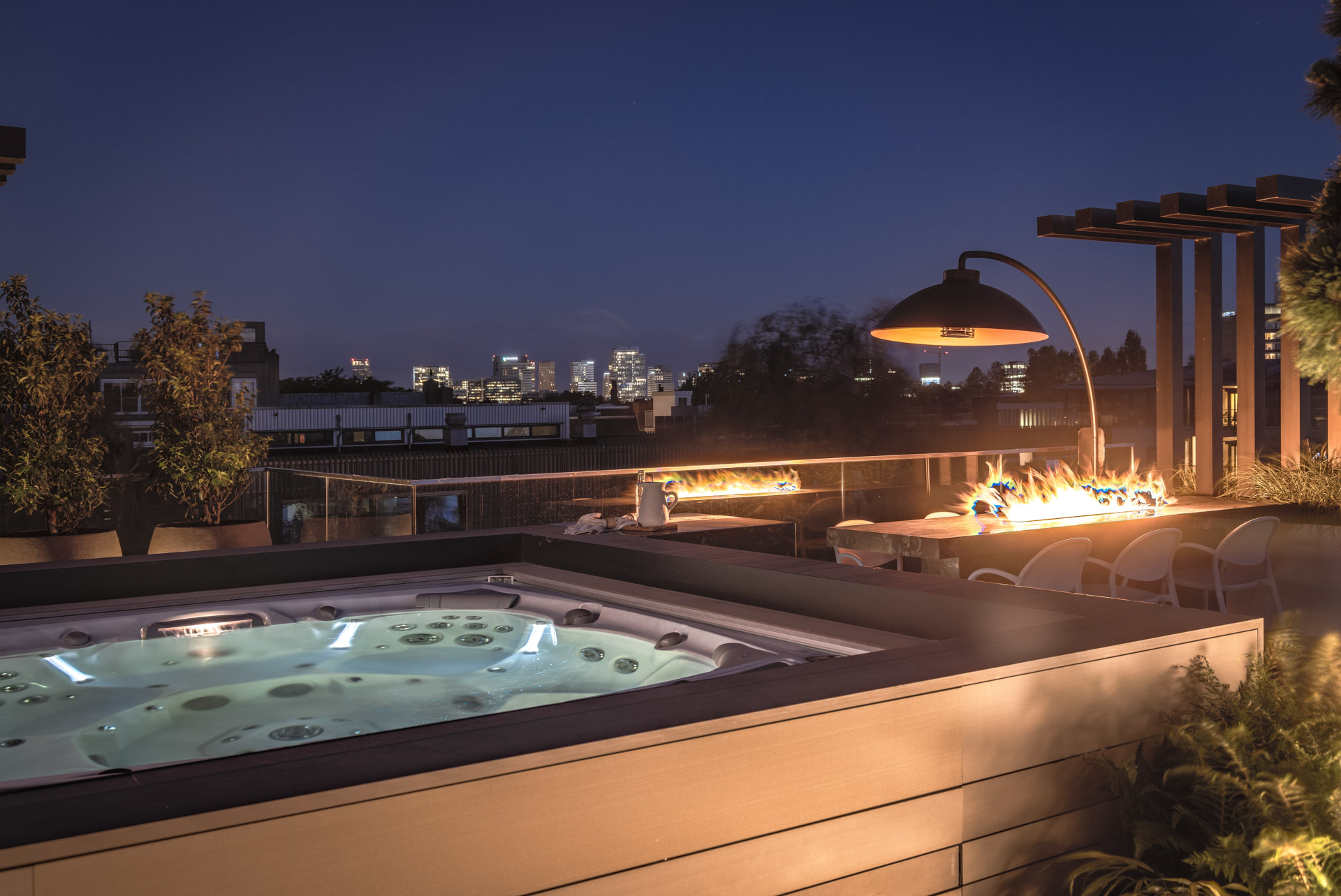 dakterras in de avond met verlichte jacuzzi en eettafel met gashaard