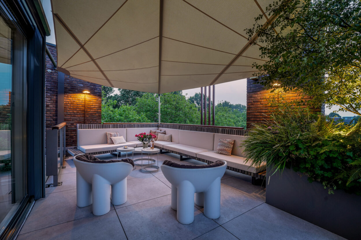 loungehoek op het dakterras met zonnedoek er boven.