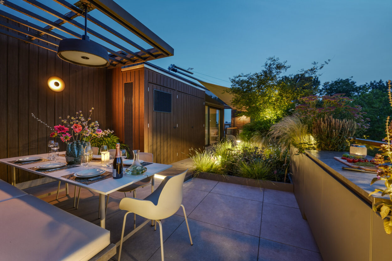 Daktuin in het avondlicht met sfeerspotjes.