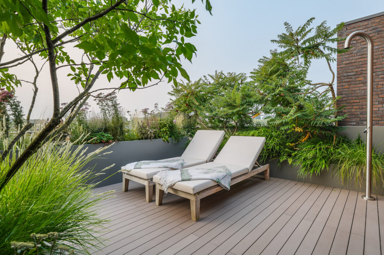 Esthec terras met buiten douche tussen de groene borders in.